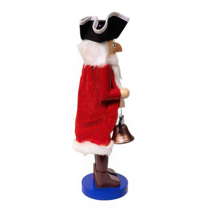 Side View of a Santa Claus Figurine in a Red Velvet Coat with White Fur Trim Holding a Brass Bell on a Blue Base