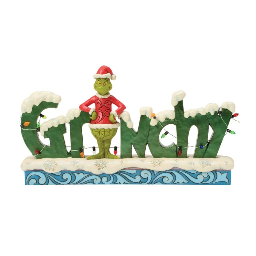 Whimsical Christmas Display with the Grinch Standing on a Snowy Green Sign Spelling out grinch and Wrapped Lights Nearby